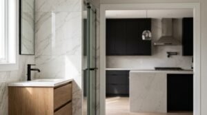 Modern floating light oak vanity with a white stone countertop, undermount sink, curved matte black mixer tap, backlit LED round mirror, and white marble wall tiles next to a walk-in glass shower.