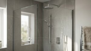 Modern walk-in shower enclosure featuring textured grey stone tiles, chrome wall-mounted overhead rain shower head, adjustable handheld shower wand on a slide rail, concealed thermostatic mixer valve, and a frameless glass screen.
