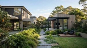 A contemporary dual-occupancy property featuring a two-story main residence and a detached timber-clad secondary dwelling separated by a landscaped stone walkway and outdoor lounge deck
