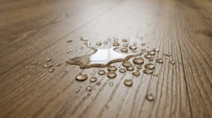 Close-up of waterproof wood-look luxury vinyl flooring with water droplets, demonstrating a durable, moisture-resistant flooring solution for laundry rooms and other wet areas