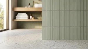 Modern laundry room featuring sage green vertical wall tiles paired with terrazzo floor tiles, timber shelving, and minimalist design