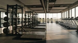 Modern commercial gym with strength training racks, treadmills, and dedicated workout zones in a spacious fitness facility
