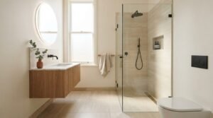 Warm luxury ensuite bathroom with floating fluted oak vanity, backlit round mirror, travertine tiles, frameless glass walk-in shower, and matte black fixtures
