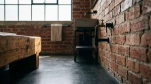 Industrial-style bathroom with exposed brick walls, dark concrete flooring, a rustic wood vanity, and black metal fixtures