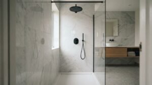 Ceiling-mounted matte black round rainfall shower head with handheld sprayer, glass enclosure, and white marble wall tiles