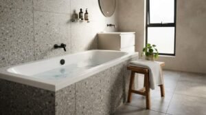Built-in drop-in bathtub with terrazzo tile surround and matte black wall-mounted faucet in a modern bathroom