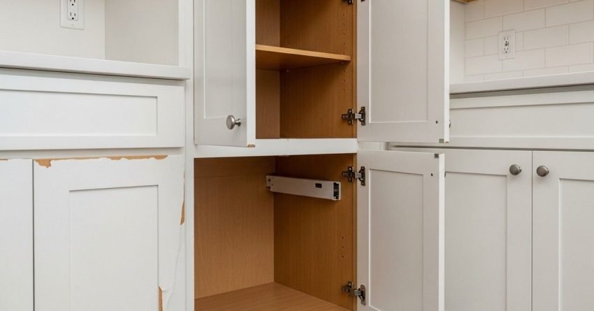 Refaced kitchen cabinets showing peeling veneer misaligned doors and worn cabinet interiors