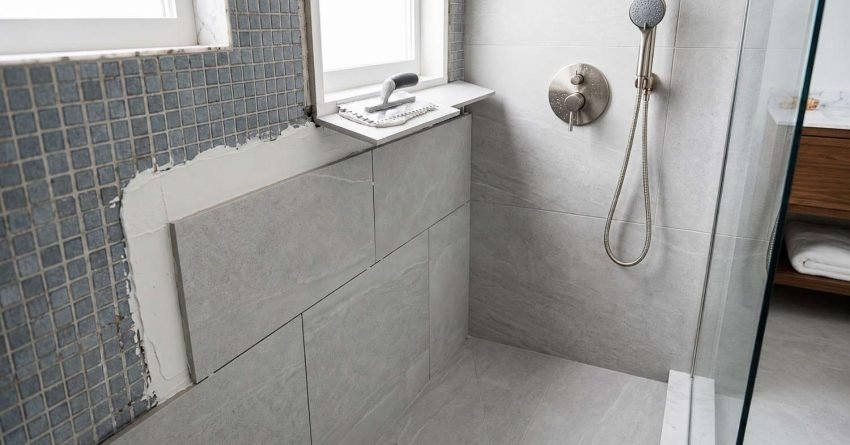Modern grey porcelain shower tile installation in progress next to blue mosaic wall